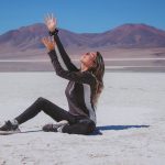 Woman raising arms on a vast white salt flat